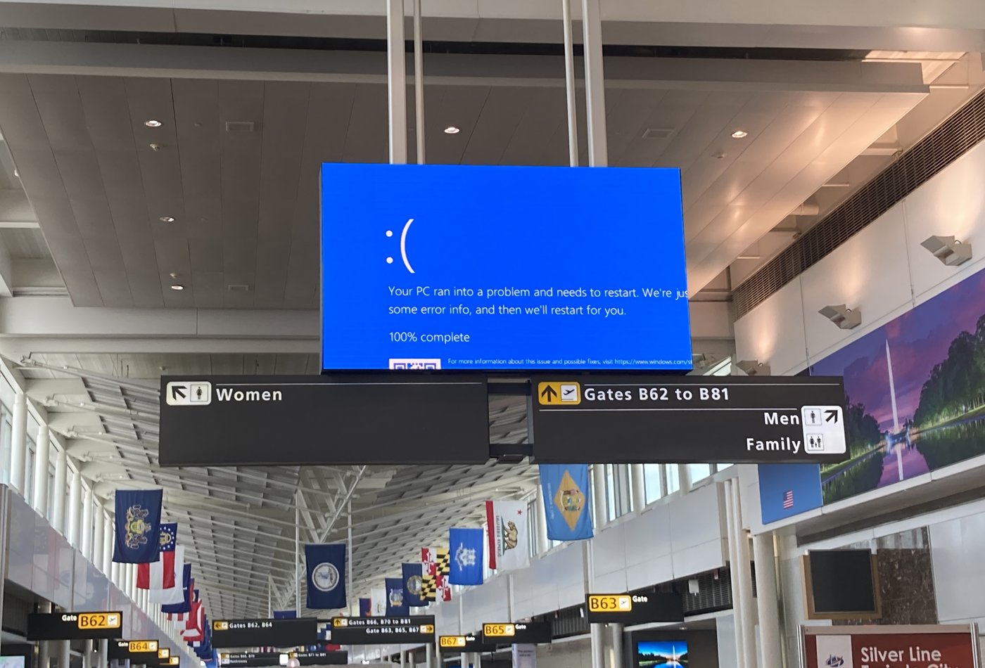 Departure boards at Dulles Airport showing Windows blue screens during the CrowdStrike outage