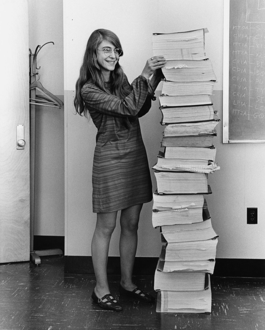 Margaret Hamilton standing next to a stack of Apollo Guidance Computer source listings
